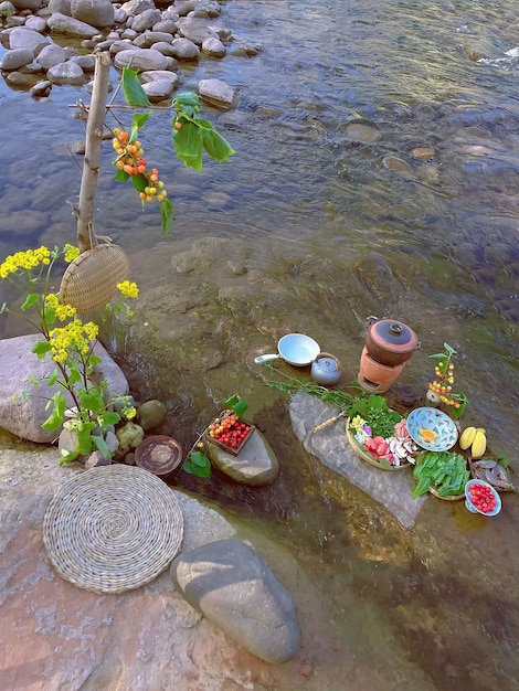 A river with a bunch of flowers and a fruit and a pot of water