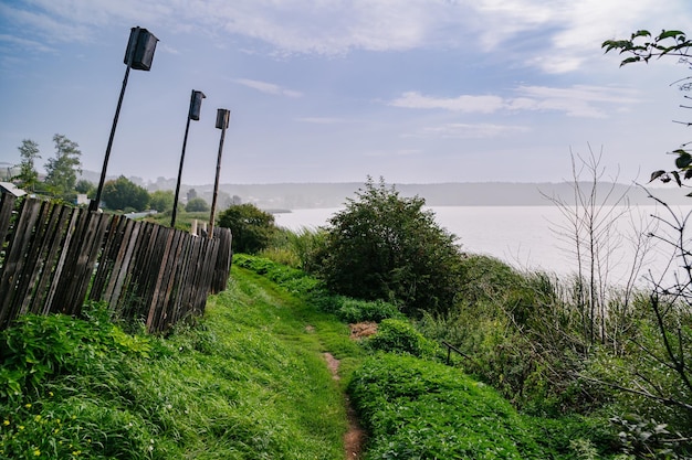 Riverbank Bliss Green Path with Wooden Fence and Feeders