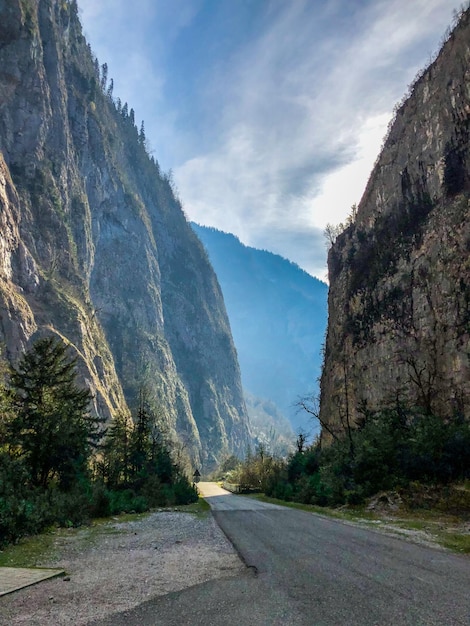 Photo road amidst trees and mountains against sky