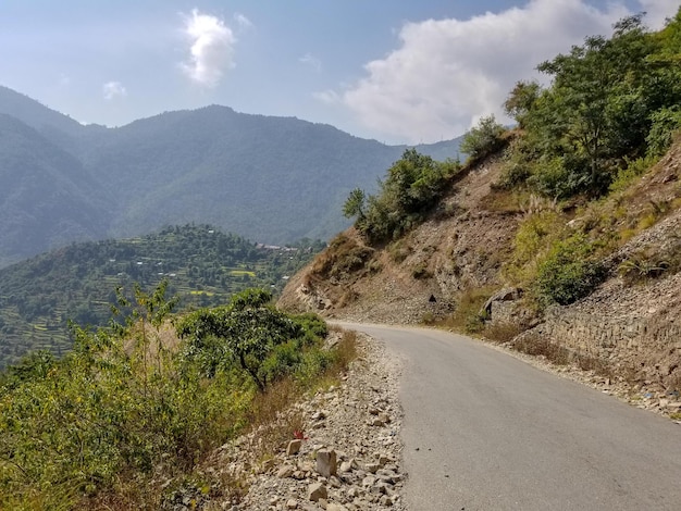 Photo road amidst trees and mountains against sky