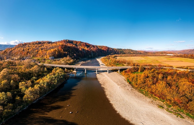 Road bridge over narrow river leading to terracotta forest