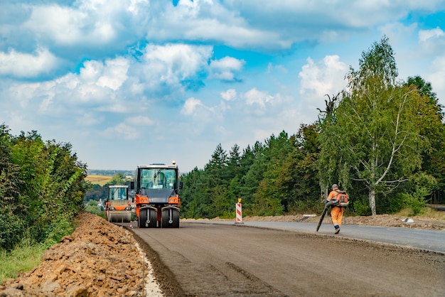 Road construction works with roller compactor machine and asphalt finisher 