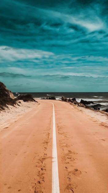 Photo road covered in the sand surrounded by the sea and rocks under a blue sky in rio de janeiro