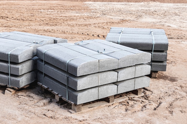 Road curbs in a pack. Curbstone prepared for laying on the construction site. Road works.