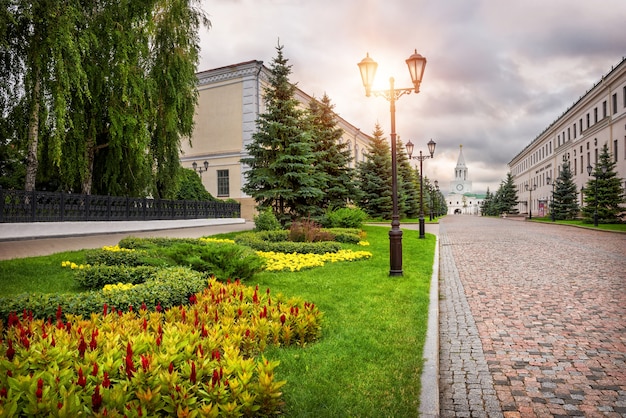 The road from stone blocks to the Spasskaya tower in Kazan Kremlin and beautiful flowers