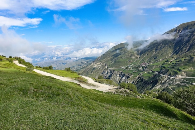 A road in the mountains of Dagestan with large mountains in the background and clouds Russia