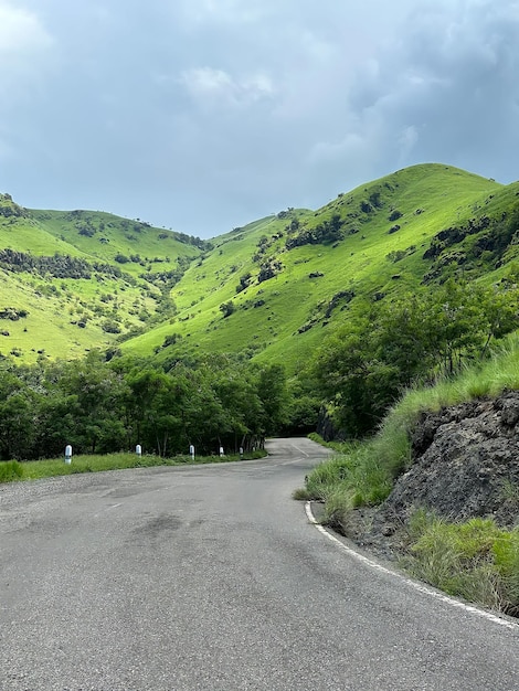 A road in the mountains with green hills and a white stripe.