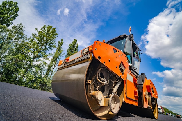 Road repair compactor lays asphalt Heavy special machines Asphalt paver in operation Side view Closeup