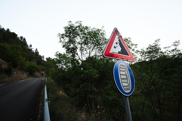 Road sign falling stones traffic sign caution possible falling rocks with compulsory snow chains aboard car in winter