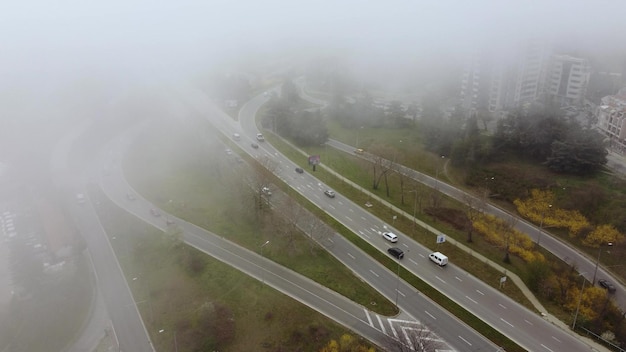 Road traffic in the city in the fog at the summer day aerial view