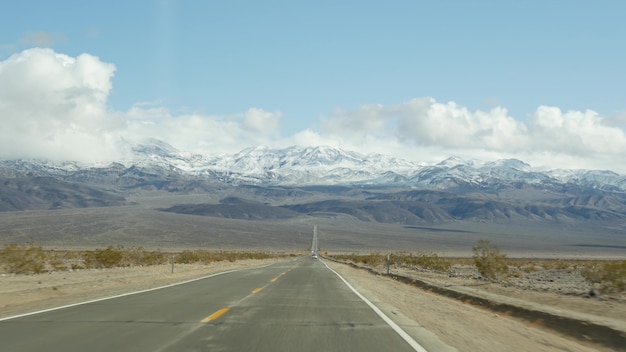 Road trip to Death Valley, driving auto in California, USA. Hitchhiking traveling in America. Highway, mountains and dry desert, arid climate wilderness. Passenger POV from car. Journey to Nevada.