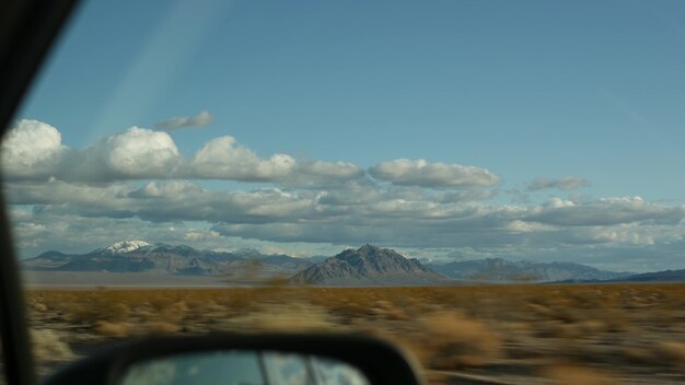 Road trip, driving auto from Death Valley to Las Vegas, Nevada USA. Hitchhiking traveling in America. Highway journey, dramatic atmosphere, clouds, mountain and Mojave desert wilderness. View from car