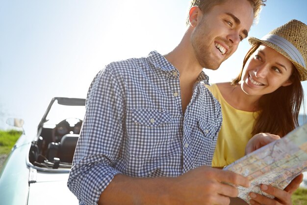 Road trip travel and couple with map by car on summer holiday vacation and weekend getaway by ocean Adventure freedom and happy man and woman reading paper for directions navigation and journey