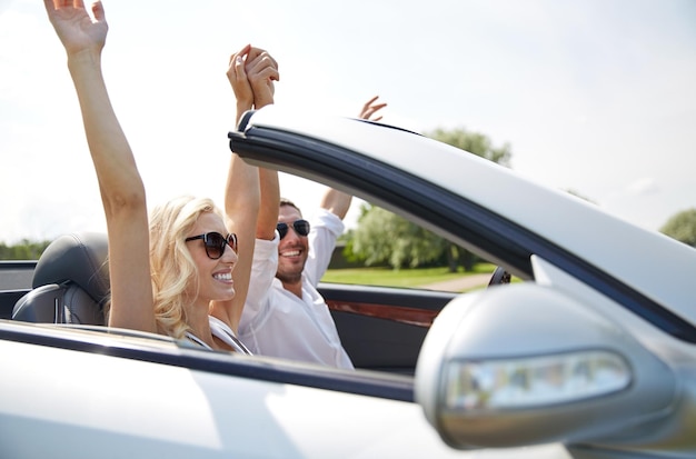 road trip, travel, dating, couple and people concept - happy man and woman driving in cabriolet car outdoors