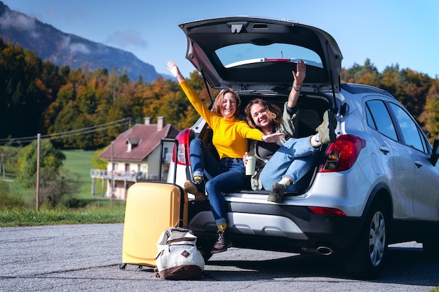 Road trip -  Two teenager smiling girls sitting in the boot