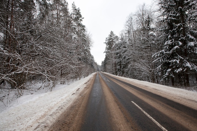 The road in the winter season, the roadway is covered with melted snow after cleaning and a large number of cars that drove through it