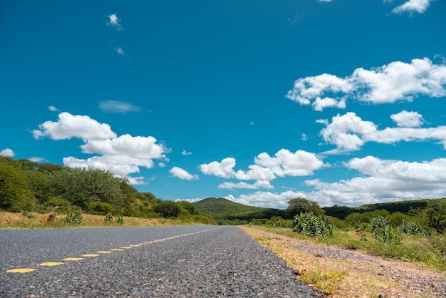 A road with a yellow stripe and a blue sky with clouds