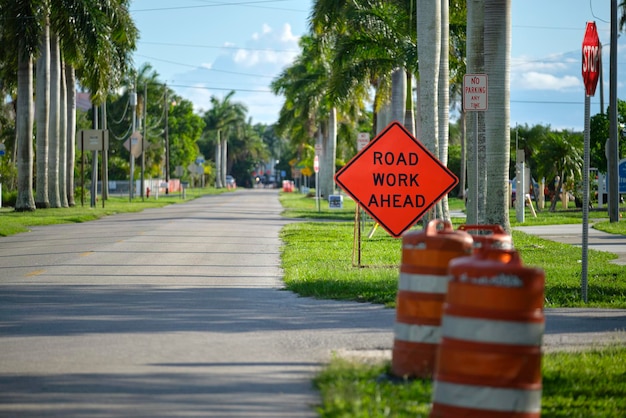 Road work ahead sign and barrier cones on street site as warning to cars about construction and utility works