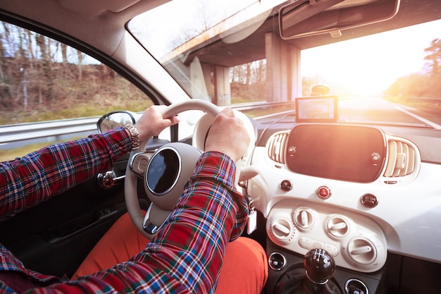 Roadtrip - mans hands on the wheel and autobahn in the background