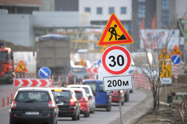 Roadworks warning traffic signs of construction work on city street and slowly moving cars