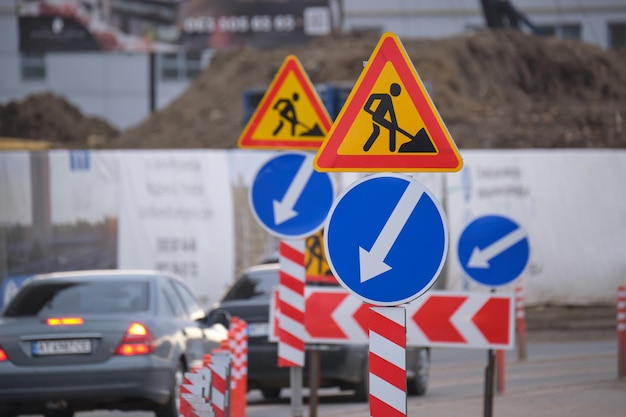 Roadworks warning traffic signs of construction work on city street and slowly moving cars