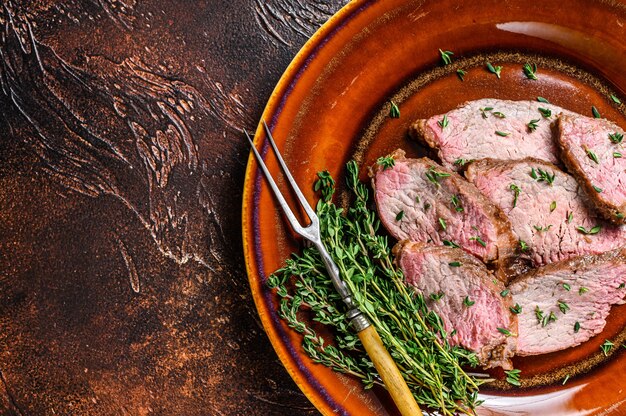 Roast beef tenderloin steak bbq on a rustic plate cutting board