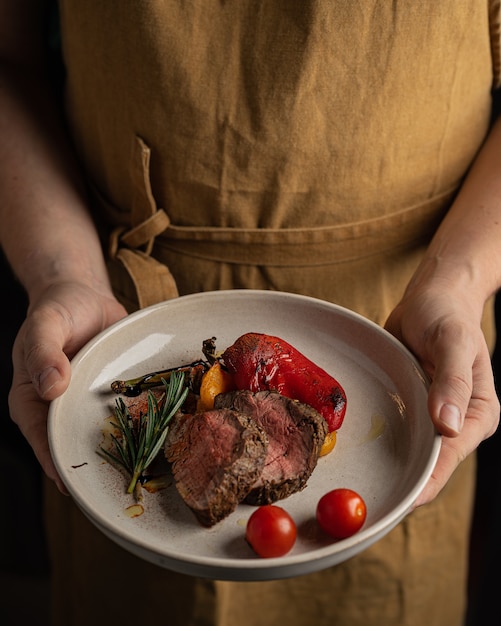 Roast beef with vegetables in the plate hanging by chef