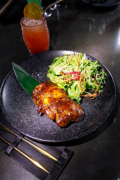 Roast duck with salad on a black plate