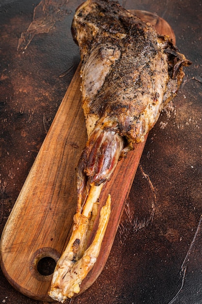 Roast lamb leg meat with herbs and spices on a cutting board Dark background Top view