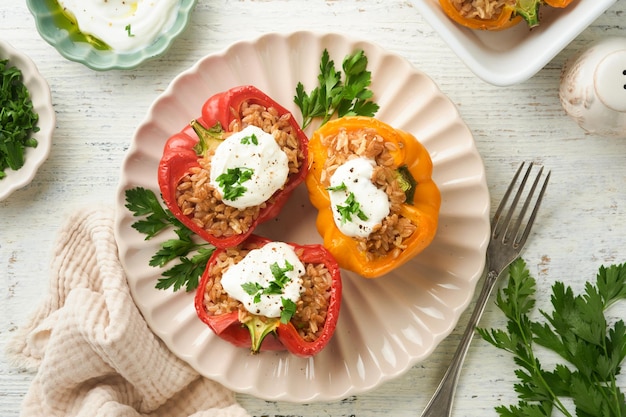 Roast stuffed red and yellow bell peppers with couscous brown rice and spelled with Greek sauce and olive oil on rustic wooden background Healthy dinner eating Autumn cozy dinner concept Top view