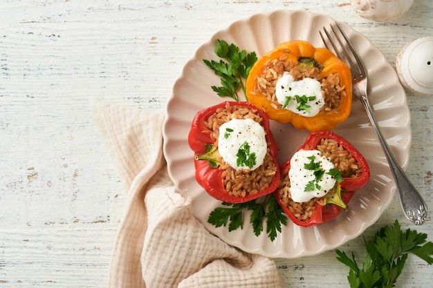 Roast stuffed red and yellow bell peppers with couscous brown rice and spelled with Greek sauce and olive oil on rustic wooden background Healthy dinner eating Autumn cozy dinner concept Top view