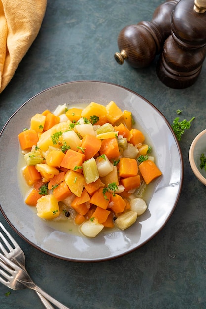 Roasted or baked root vegetables with fresh herbs orange vegetables on plate Vegan food