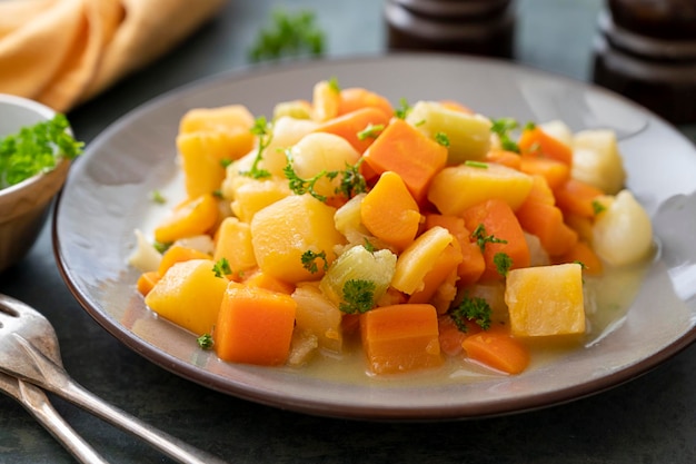 Roasted or baked root vegetables with fresh herbs orange vegetables on plate Vegan food