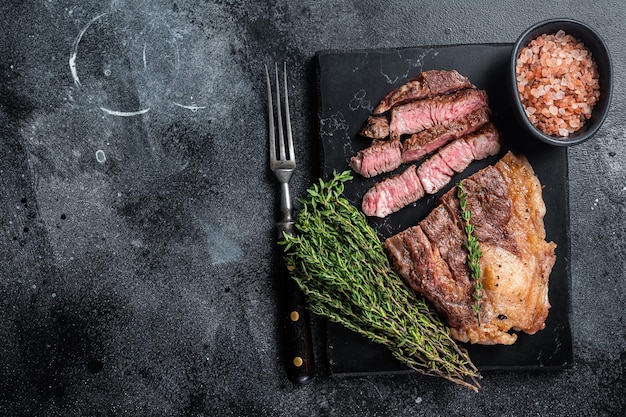 Roasted bbq Chuck Roll beef steaks with herbs Black background Top view Copy space