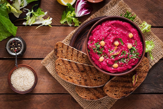 Roasted Beet Hummus with toast in a ceramic bowl on a dark background