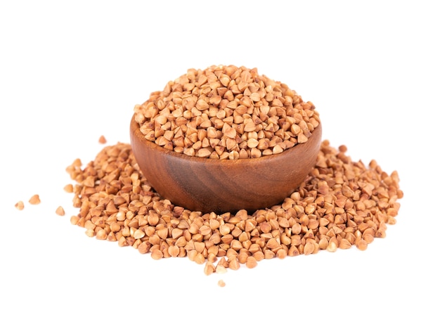 Roasted buckwheat grains in wooden bowl, isolated on white background. Dry brown buckwheat groats.