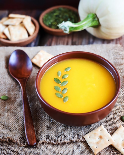 Roasted butternut squash cream soup with pumpkin seeds, pumpkin soup on rustic background