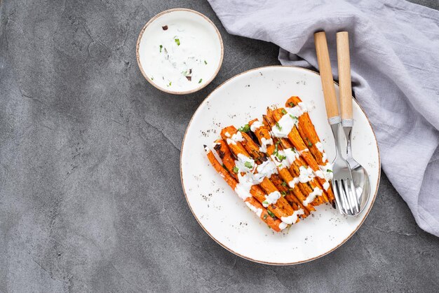 Roasted carrot sticks on a white plate Baked carrots with herbs and spices on gray background