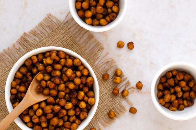 Roasted chickpeas in white bowls and a wooden spoon