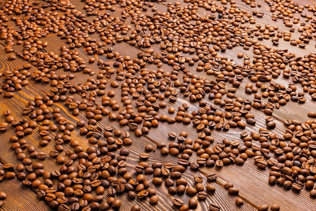 Roasted coffe beans spreaded over wooden board full frame background with linear perspective