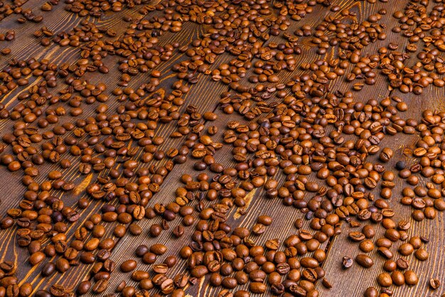 Roasted coffe beans spreaded over wooden board full frame background