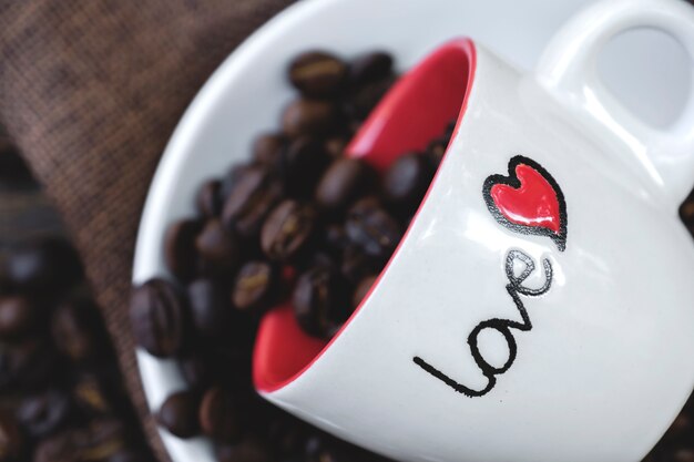 Photo roasted coffee bean in love cup on wodden table surrounded 