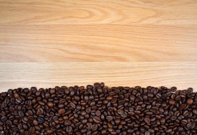 Roasted coffee beans on brown wooden background copy space