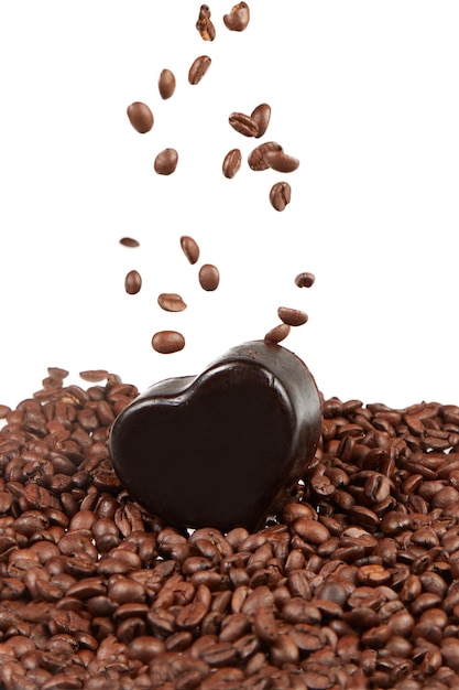 Roasted coffee beans falling into a dark heart shaped soap bar