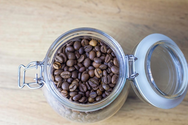 Roasted coffee beans in glass can on wooden table