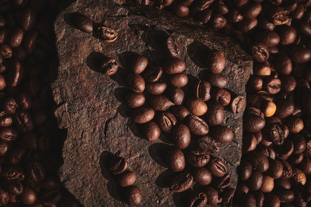 Roasted coffee beans on stone pedestal brown background