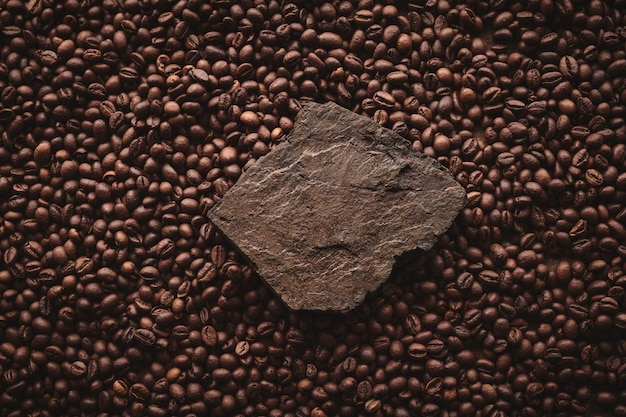 Roasted coffee beans on stone pedestal brown background