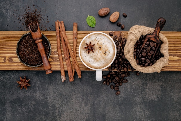 Roasted coffee beans with coffee powder and flavourful ingredients for make tasty coffee setup on dark stone.