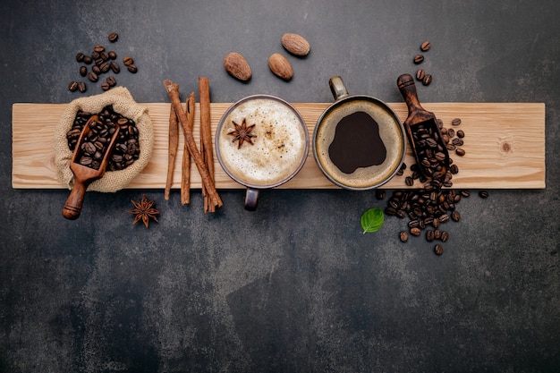 Roasted coffee beans with coffee powder and flavourful ingredients for make tasty coffee setup on dark stone.