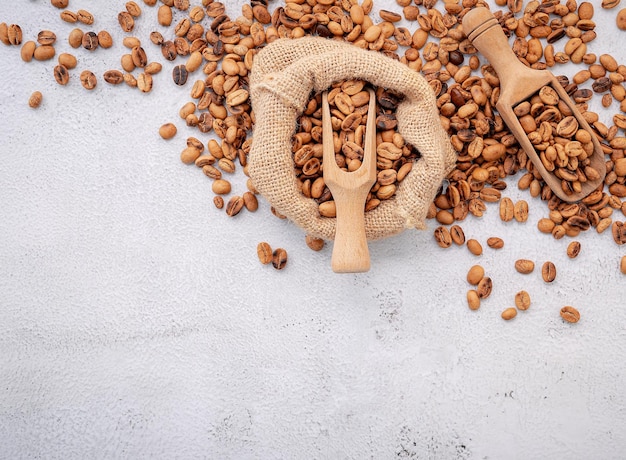 Roasted coffee beans with scoops setup on white concrete background